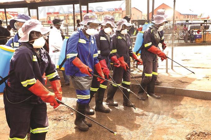 City of Harare workers spray chemicals at Market Square bus rank